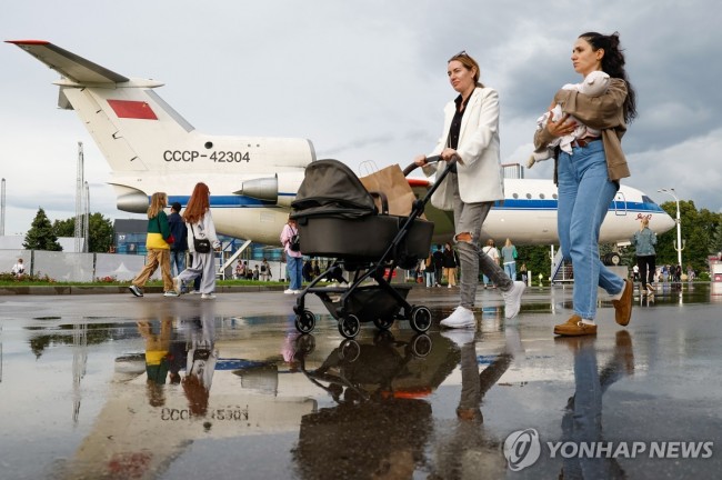 아기와 함께 소련 비행기가 전시된 러시아 박람회장 거니는 러시아 여성들